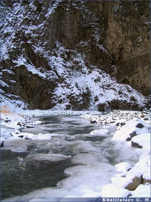 Обледеневшей водопад еле заметен на фоне скалы,  Обледеневшей водопад еле заметен на фоне скалы